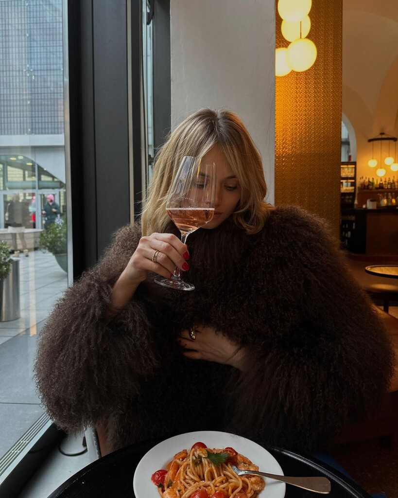 15 Payday treats to move from wishlist to your wardrobe - Olga loeffler in ducie coat drinking wine and enjoying her pasta 